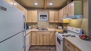 Une cuisine avec des meubles de rangement en bois, un réfrigérateur blanc, une cuisinière et un évier.