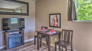 Un coin repas avec une table en bois, des chaises, un tableau encadré et une fenêtre avec des rideaux.