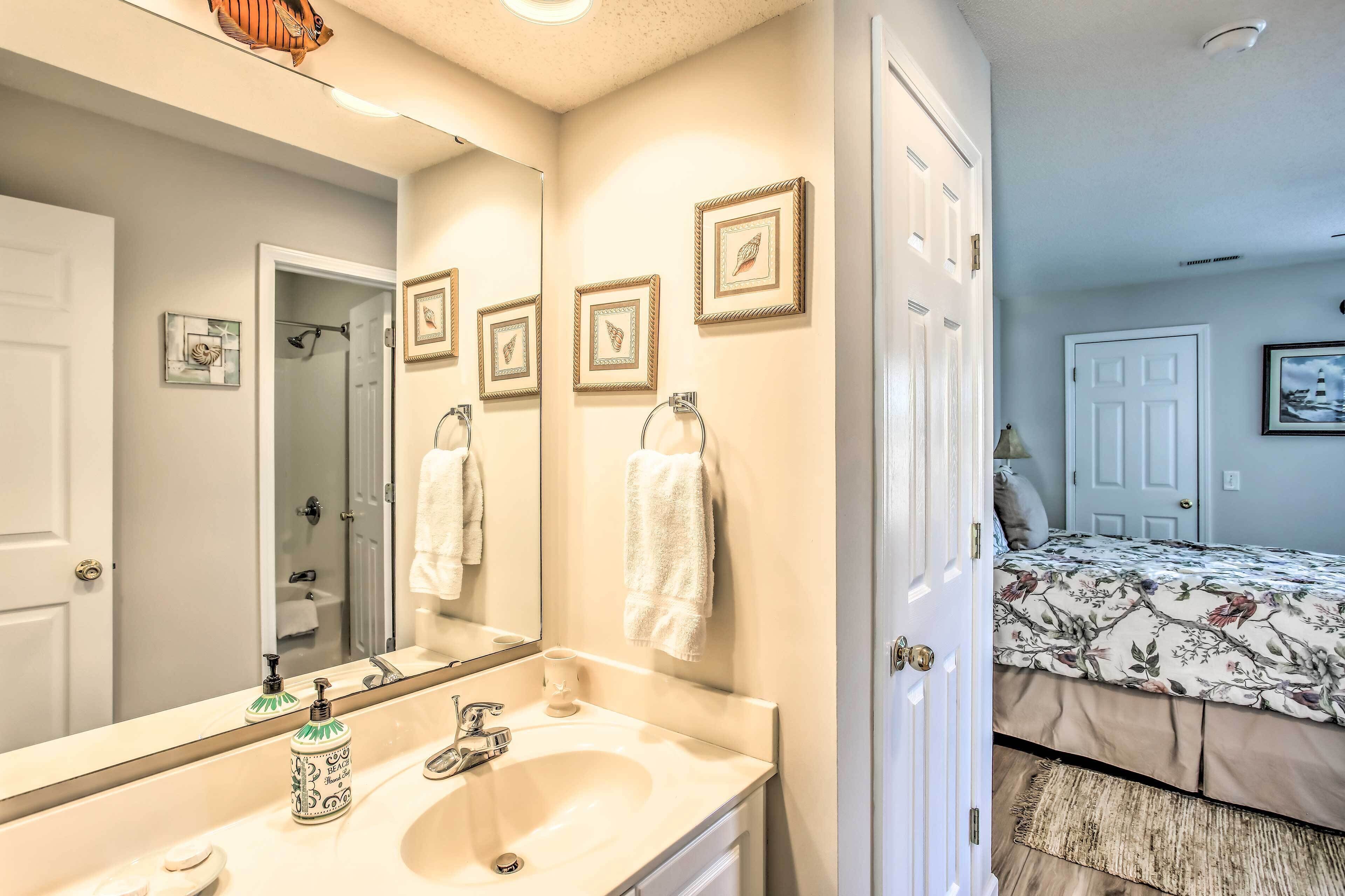 A bathroom with a sink, mirror, and framed pictures on the wall.
