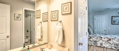 A bathroom with a sink, mirror, and framed pictures on the wall.