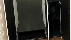 A walk-in closet with a metal rod for hanging clothes, a shelf unit, and a door with a handle. - Cozy Studio Guest Suite (Ames)