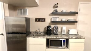 A compact kitchen with a stainless steel refrigerator, a built-in microwave, a coffee maker, and a toaster. - Cozy Studio Guest Suite (Ames)