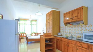 A compact kitchen with wooden cabinets, a microwave, and a dining area with a table and chairs.