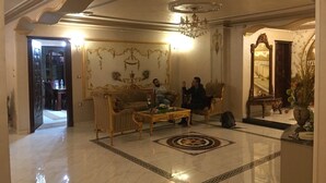 Un'ampia hall con pavimento in marmo, arredi decorati e un grande lampadario.