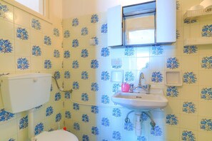 A bathroom with blue floral tiles, a toilet, a sink, and a mirror. - Faros Pende, Gaios Studio, sleeps 2, near beach, sea views (Gaios)