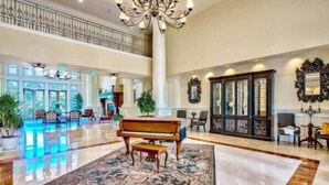 A spacious lobby with a grand piano, a large ornate rug, and a high ceiling with a chandelier. - Enjoy This Elegant Coastal Condo:, King-Suite,Full kitchen,Pool, Hot Tub,Balcony (Miramar Beach)