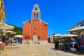 A church with a bell tower, outdoor seating, and potted plants.