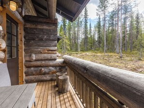 Une cabane en rondins avec une terrasse en bois et vue sur une forêt.