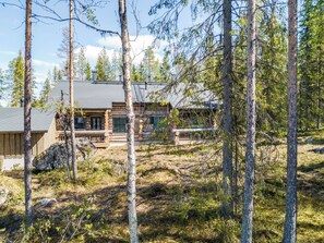 A cabin with a stone exterior, a wooden deck, and a large window.