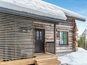 Une cabane en rondins avec une porte en bois et une fenêtre dotée de volets.