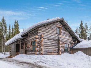 Une cabane en rondins avec un toit en pente, des volets en bois et une véranda.