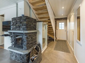 Une cheminée en pierre avec un téléviseur fixé au-dessus, un escalier en bois et une porte dotée d’une fenêtre.