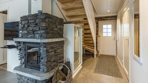Ein Steinkamin mit einem Fernseher darüber, eine Holztreppe und eine Tür mit Fenster.