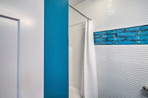 Een badkamer met een witte, geribbelde wand, een blauwe accentwand en een douchegordijn.