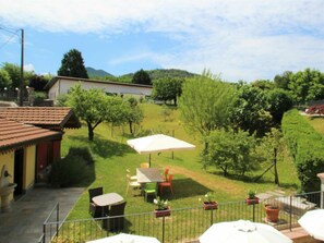 Un patio con asientos al aire libre, un edificio pequeño y vistas de un paisaje montañoso.