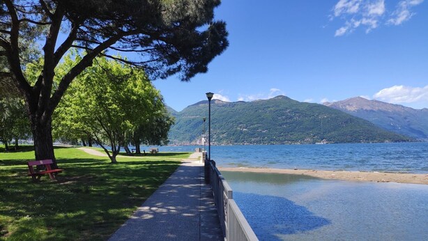 A paved walkway beside a lake with a bench and a lamppost. - Lovely apartment for 3 people with WIFI, TV and patio (Germignaga)