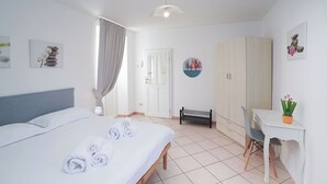 A hotel room with a bed, a desk, a bench, and a wardrobe. - Lovely apartment for 3 people with WIFI, TV and patio (Germignaga)