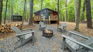 A cabin with a deck, surrounded by trees, and a fire pit with chairs. - Cozy Pet-Friendly w Fire Pit, Wifi & Pool Access (Hedgesville)