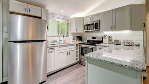 A modern kitchen with stainless steel appliances, white cabinetry, and a granite countertop. - Cozy Pet-Friendly w Fire Pit, Wifi & Pool Access (Hedgesville)