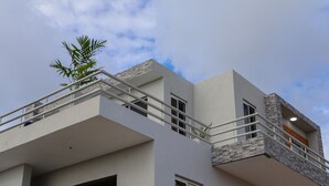 A modern multi-story building with a balcony, large windows, and a visible door. - This brand new Villa, modern amenities,  Pool deck and ocean views (Ceder Village)