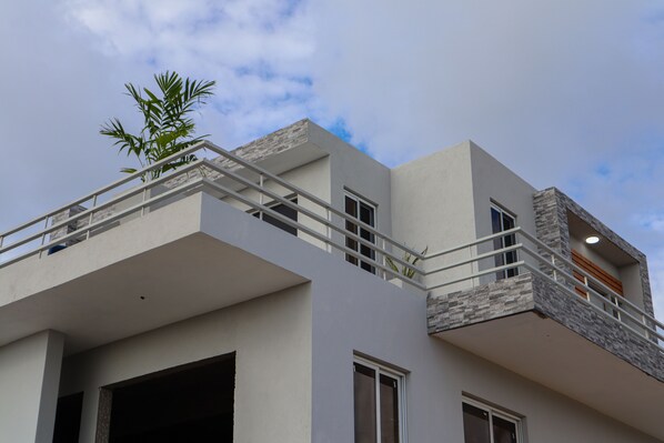 Ein modernes, mehrstöckiges Gebäude mit Balkon, großen Fenstern und einer sichtbaren Tür.