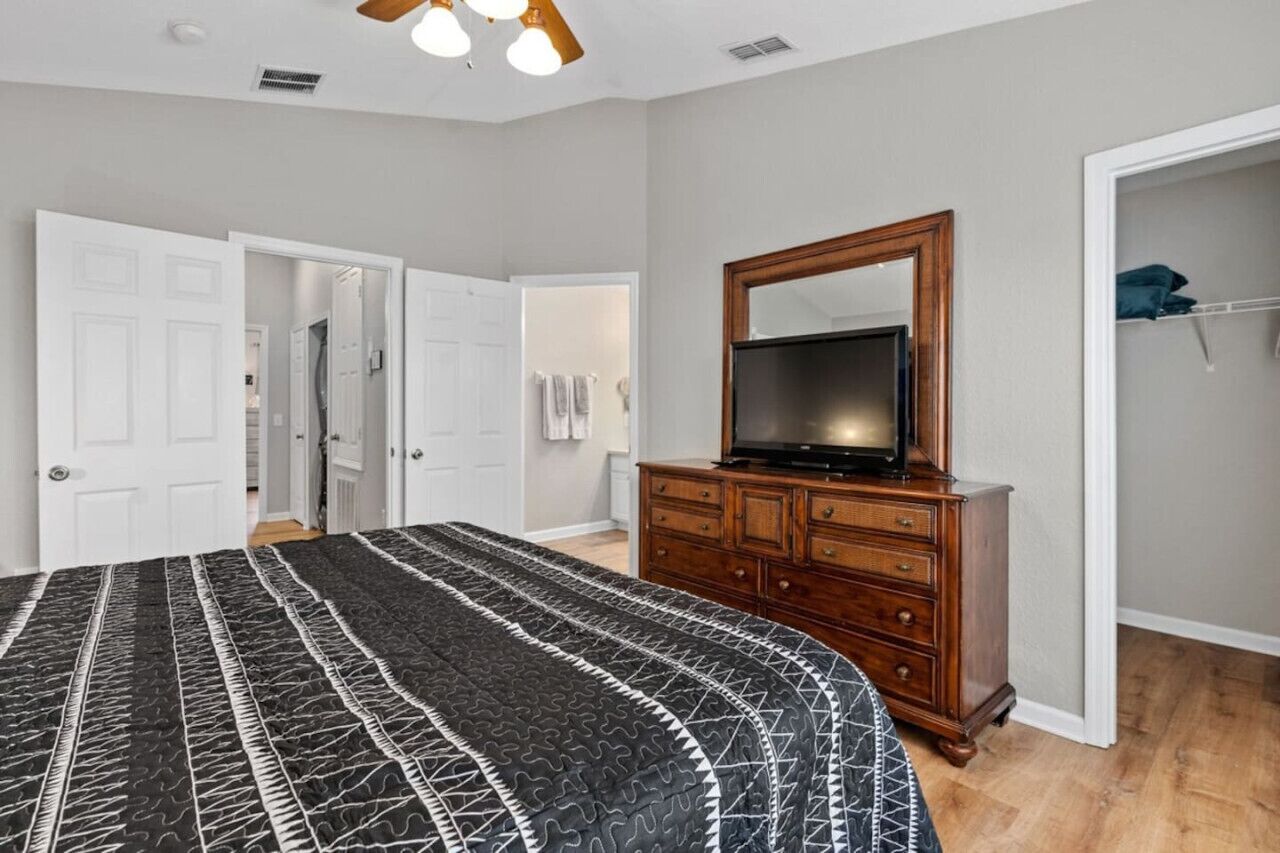 A bedroom with a bed, a dresser, a TV, and a closet.