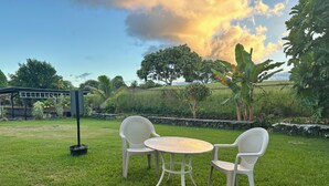 A grassy outdoor area with two white plastic chairs and a round table. - Puakenikeni Hilo Hale (Hilo)