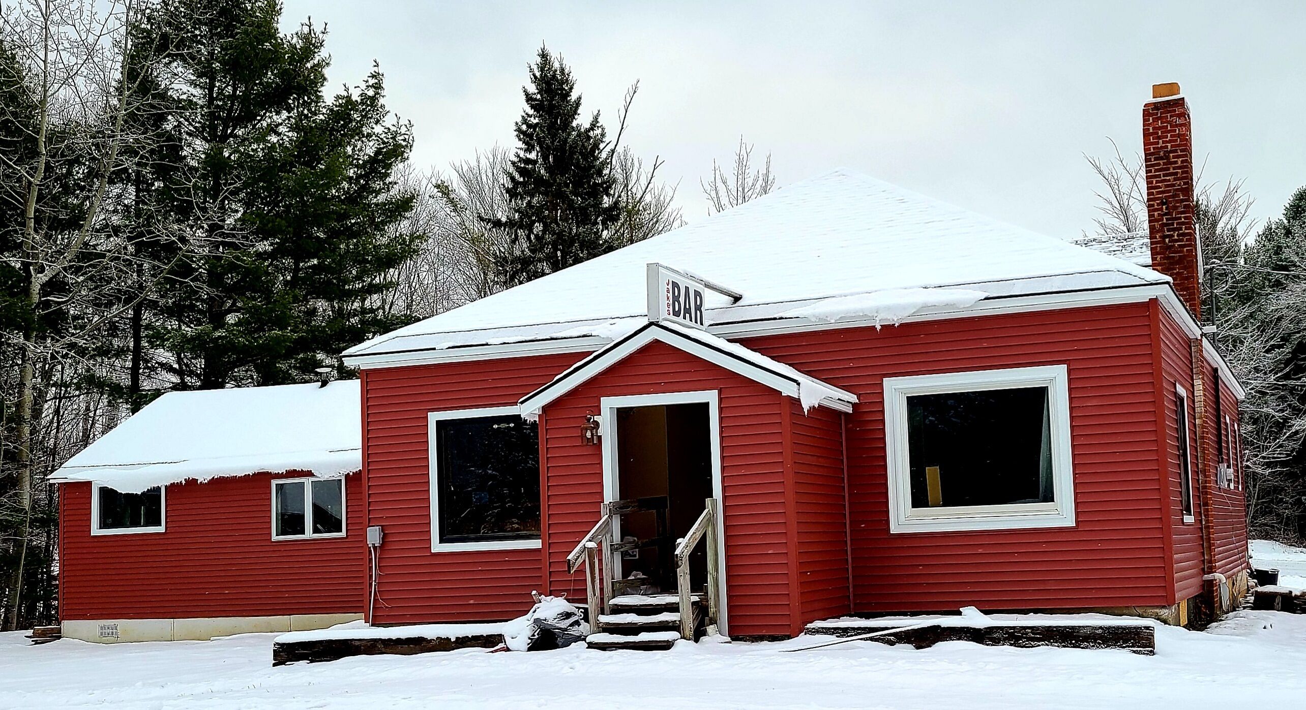 A red wooden house with a chimney, a front door, and a window.