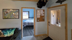 Een kamer met een bed, een prikbord, een berenhoofd decoratie en een deur met een raam.