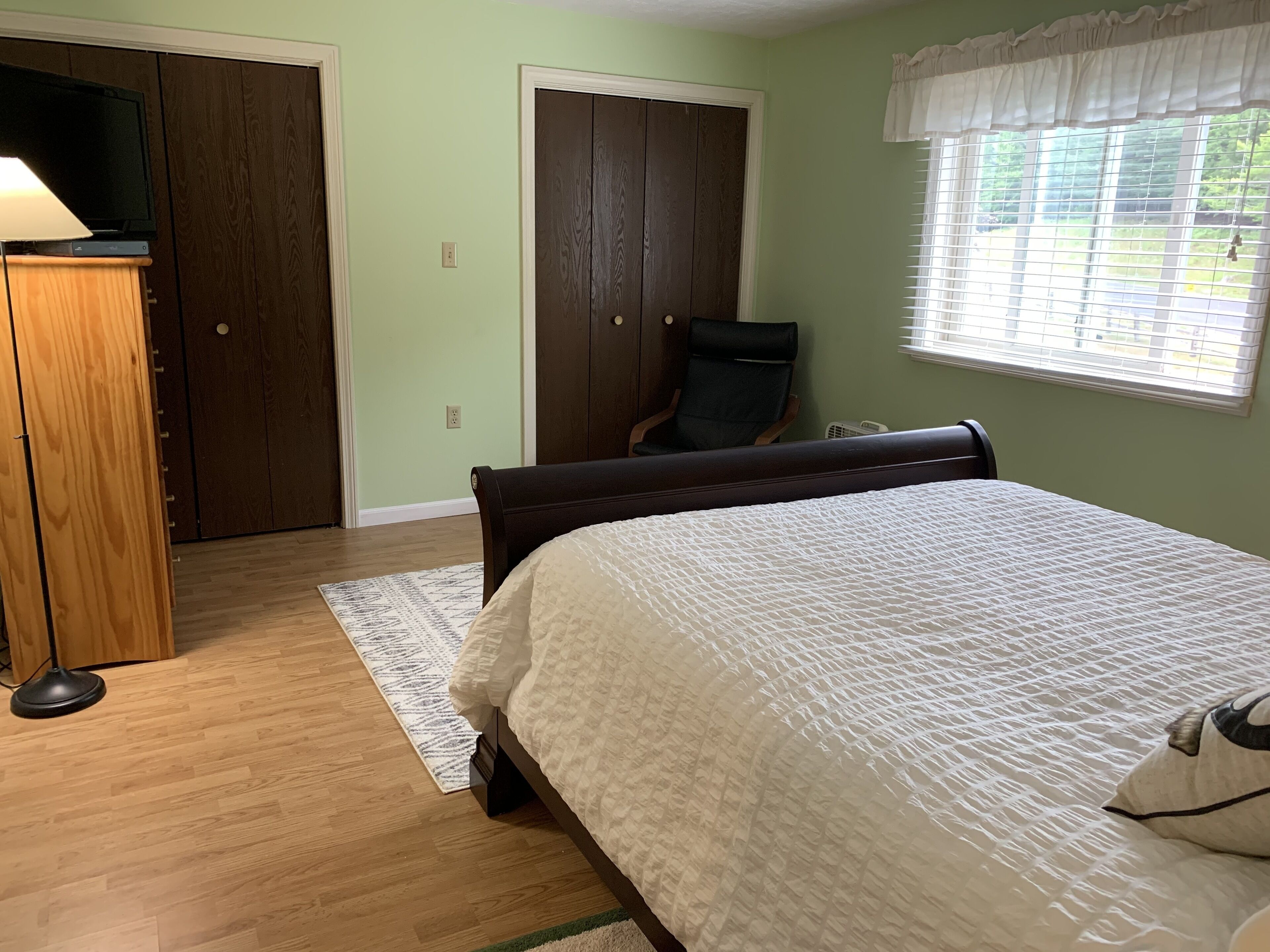 A bedroom with a bed, a chair, a desk, and a wardrobe.