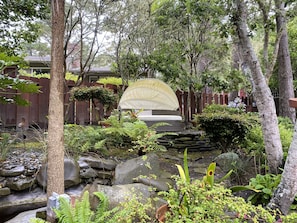 Escape to a serene oasis surrounded by lush greenery and a tranquil water feature.