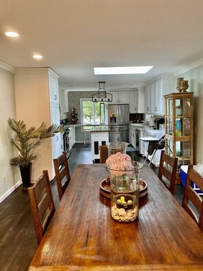 Enjoy meals in the spacious kitchen and dining area, featuring a central island, stainless steel appliances, and a dining table with a glass centerpiece.
