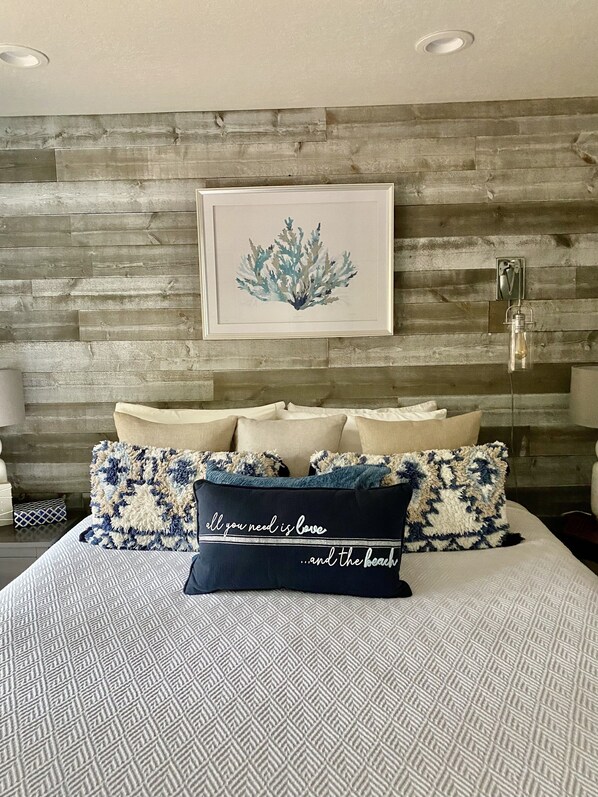Relax in a stylish bedroom with a patterned bedspread and multiple pillows, featuring a framed artwork above the bed.