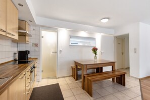 Une cuisine moderne avec des meubles en bois, un four encastré et un coin repas comprenant une table et un banc en bois.