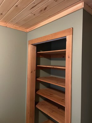 A wooden shelving unit with three shelves against a wall.