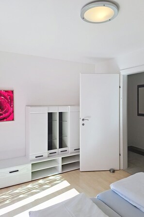 Ein Zimmer mit einem Bett, einem Kleiderschrank, einer Tür und einer Deckenleuchte.