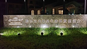 A sign for Howard Johnson's Forest Resort Yali with a marble facade and illuminated text. - Howard Johnson by Wyndham Yaan Forest Resort (Ya'an)