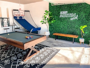A pool table with balls, a blue slide, and a green wall with "KEEP AUSTIN weird" text.