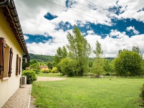 A courtyard with a building on one side, surrounded by greenery and trees.