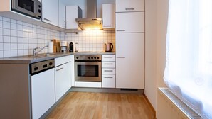 A modern kitchen with white cabinets, a built-in oven, a microwave, and a stove.