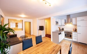 Eine moderne Wohnung mit Essbereich, Küche und Wohnzimmer, inklusive Sofa und Fernseher.