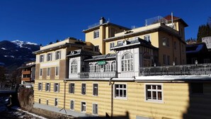 A multi-story building with a balcony, a sign reading 'ASTORIA,' and a mountain backdrop.