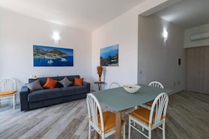 Una habitación con sofá, mesa de comedor, sillas y dos cuadros en la pared.
