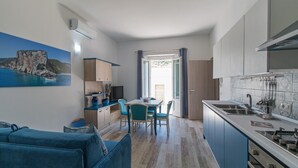 A compact living space with a kitchenette, dining area, and a sofa. - Apartment Blu with Mountain View, Balcony, A/C & Wi-Fi (DORGALI)