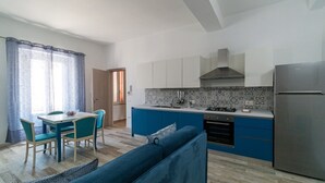 A compact kitchen with a central island, a dining area with chairs, and a sofa. - Apartment Blu with Mountain View, Balcony, A/C & Wi-Fi (DORGALI)