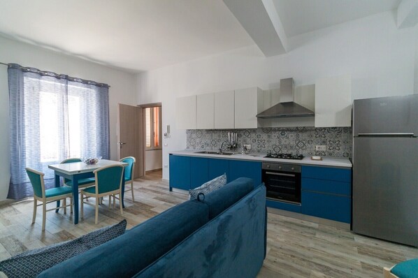 A compact kitchen with a central island, a dining area with chairs, and a sofa.