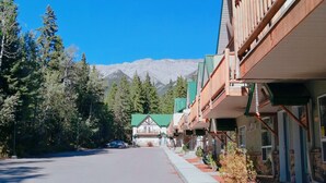 A row of wooden buildings with balconies, a clear road, and a mountain in the background.