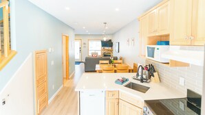 A modern kitchen with wooden cabinets, a central island, and a dining area with a sofa and table.