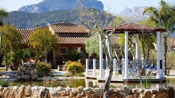 Ein traditionelles Gebäude mit Ziegeldach, Steinmauer und einem Gazebo mit weißen Säulen.