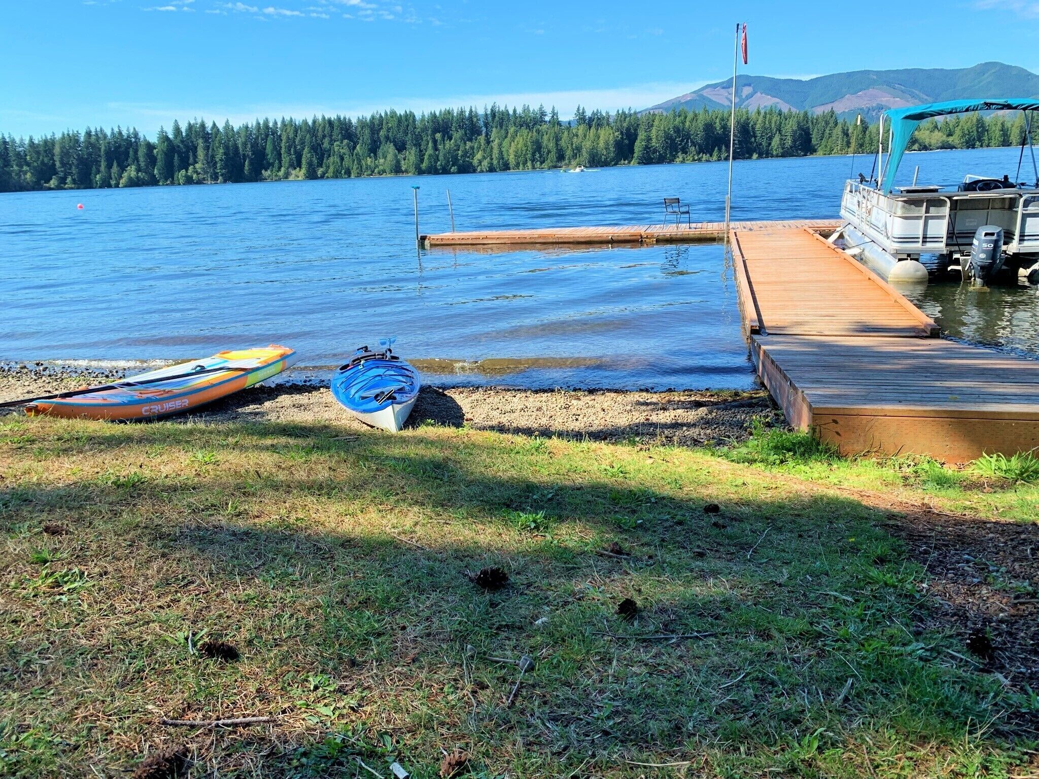 A lakeside dock with a boat and a small boat on the shore.